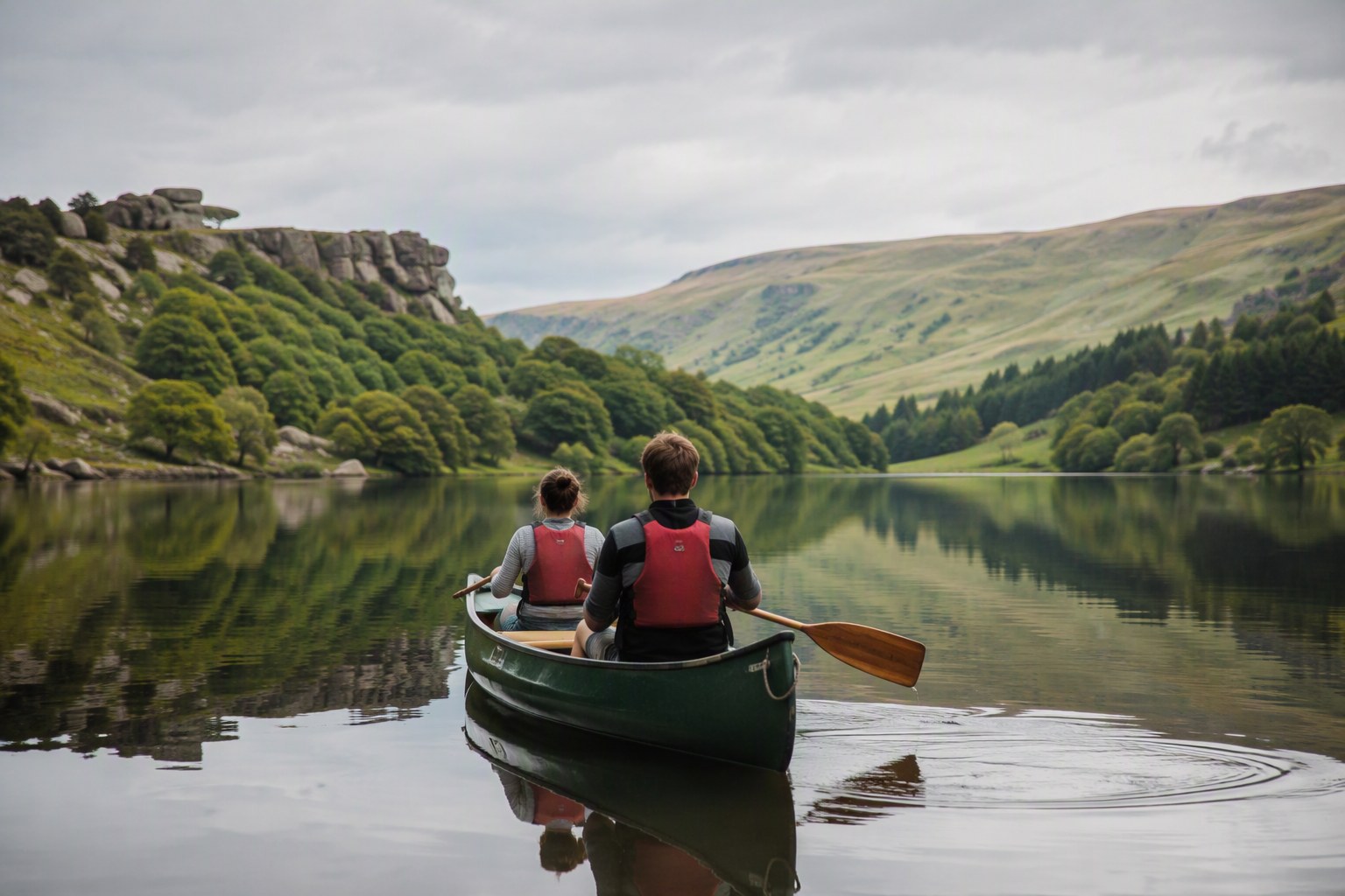 Illustrative image: two young people canoeing on a calm reservoir surrounded by green hills